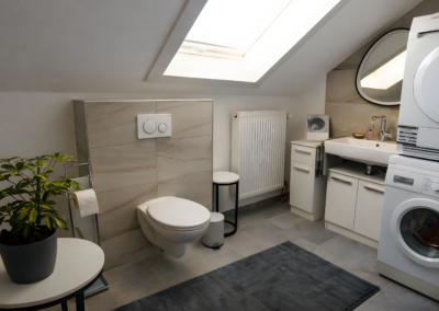 Modernes Badezimmer unter der Dachschräge mit Waschmaschine, Trockner, WC und Waschbecken in der Ferienwohnung Jaeger in Viereth bei Bamberg.
