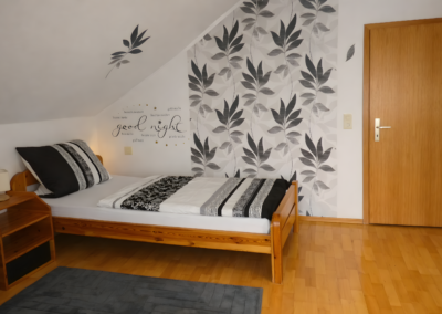 Doppelzimmer der Ferienwohnung Jaeger in Viereth bei Bamberg mit zwei Einzelbetten, Nachttischen, Lampen und moderner Wanddeko.