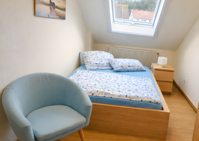 Einzelzimmer der Ferienwohnung Jaeger in Viereth bei Bamberg mit Einzelbett, Dachfenster, Stuhl und Nachttisch.